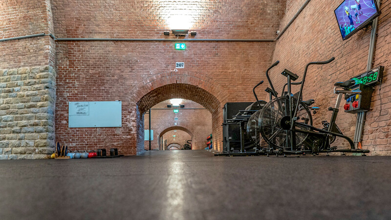 Aus der Bodenperspektive schaut man tief hinein in eine perfekt sanierte Rundbogenstrecke der Wiener Stadtbahn, deren Gewölbe von CrossZone als Fitnessstudio genutzt werden. Das Studio ist mit Fitnessmatten von WARCO ausgelegt.