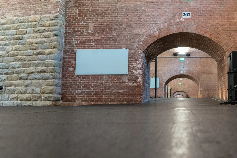 Klassische Backsteinhalle, die für eine Veranstaltung mit schwarzem Messeboden mit Puzzlezahnverbindung ausgelegt ist.