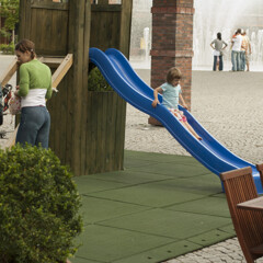 Auf dem gepflasterten Platz hat der Gastwirt einen Spielplatz für die Kinder seiner Gäste im Gartenlokal angelegt. Der Spielplatz, auf dem sich ein Kletterturm aus Holz mit Rutsche befindet, ist mit dem mobilen WARCO-Spielboden gesichert.