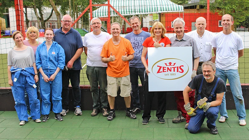 Nach getaner Arbeit stellt sich ein Zentis-Team zum Erinnerungsfoto auf. Die Männer und Frauen stehen auf grünem WARCO-Bodenbelag.