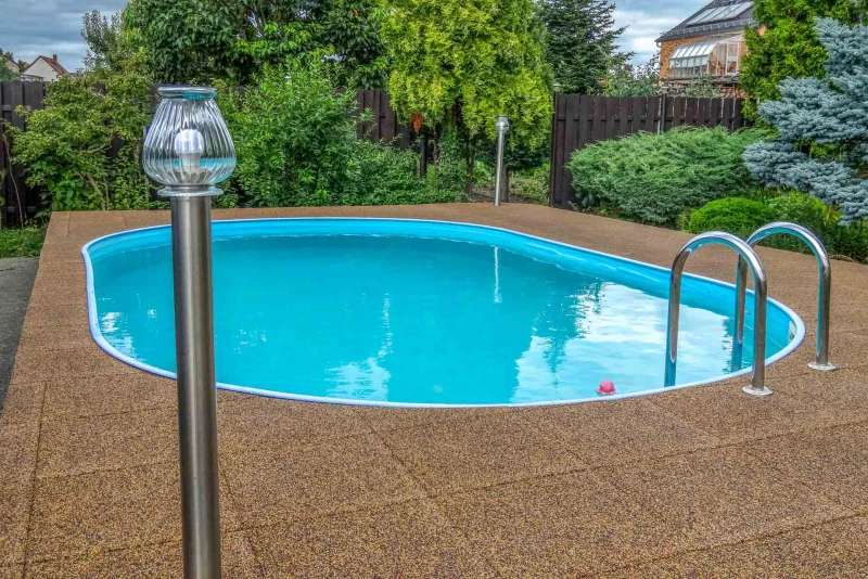 Der farblich in natürlichen  Erdtönen gehalten Umgang aus wasserdurchlässigen WARCO-Schwimmbad-Fliesen (Farbdesign Terra Cotta)  passt hervorragend in die Gartenlandschaft, in der das Schwimmbecken steht.