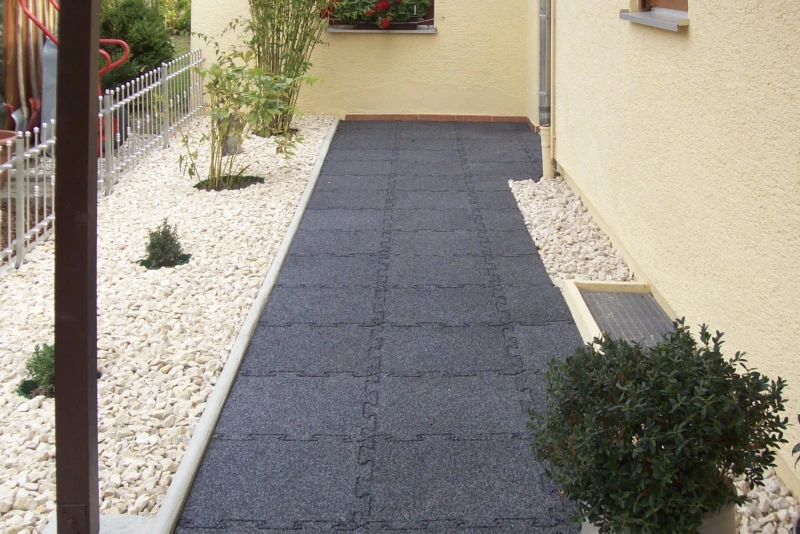 Rutsch hemmende und wetterfeste WARCO-Gehwegplatten aus Gummigranulat liegen auf dem Weg durch den Garten zum seitlich am Haus liegenden Hauseingang.